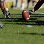 A football player gets ready to hiking a football.